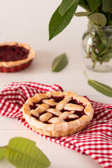 Open pie from shortcrust pastry with cherries and raspberries, a pie with a serviette on a white background