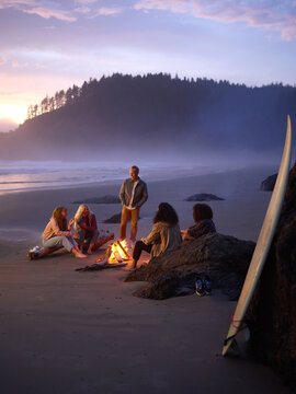 Friends relaxing around bonfire on beach