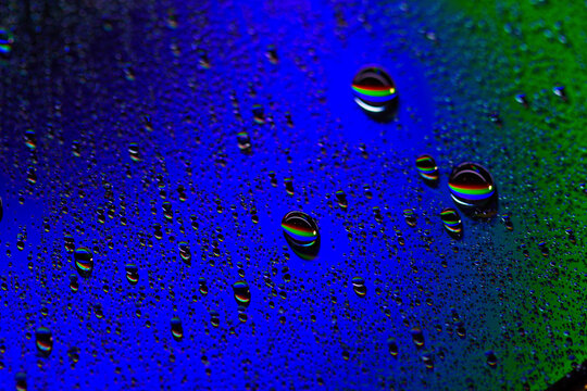 large and small water drops on a blue neon background.the reflection in the drops of red, green and blue colors.macro mode.
