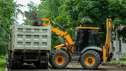 the tractor empties the earth into the body of the dump truck