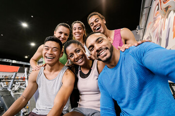Interracial gym partners taking a selfie after workout at gym.