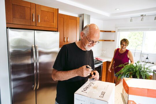 Mature couple enjoying boxing up kitchen to move.