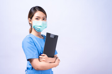 Portrait of young Asian nurse wearing surgical mask holding clipboard. concept of occupation and career