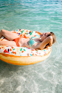 Young female model having fun in the sea with donut float