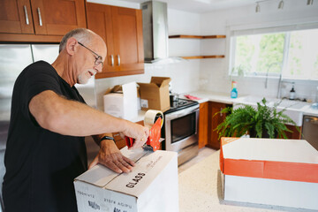 Mature man boxing up kitchen.