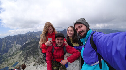 Lucky friends making selphi on peak of mountain.