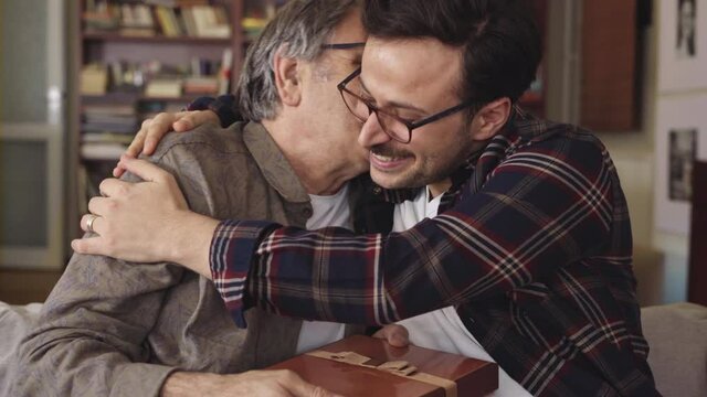 Young son embracing his father with love and giving present	
