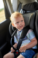 Happy little boy sits in a car seat.