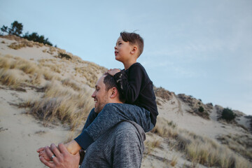 Dad giving boy shoulder ride after exploring sand dunes in Florence, OR.