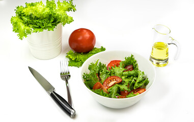 Lettuce and tomato salad with olive oil in a white deep dish on a white background. Healthy food. High quality photo
