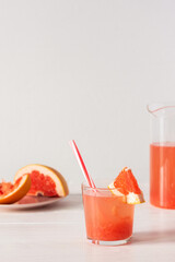 Summer refreshing grapefruit drink, jug and glasses with grapefruit pulp and juice and straws