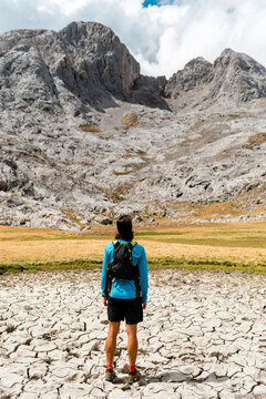 Back view of runner resting in the meadows close to white limestone peaks in Picos de Europa National Park