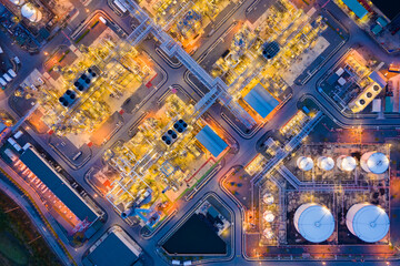 Aerial view of oil refinery plant chemical factory and power plant with many storage tanks and pipelines at sunset.