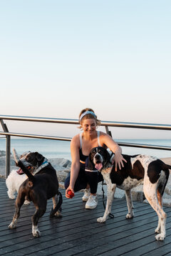 Cheerful woman playing with dogs on pier