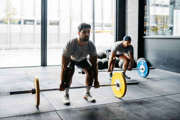 Men exercising with barbells in a crossfit box