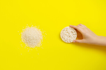 Rice cake in woman arm on a yellow background. Rice grains in the left coner.