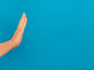 Woman hand show stop sign on blue background with copy space.