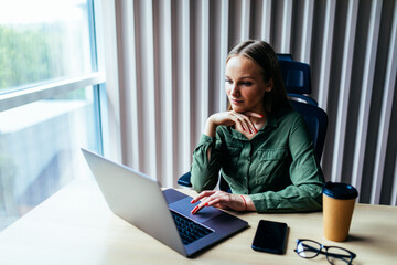 Beautiful young woman working on her laptop in her office