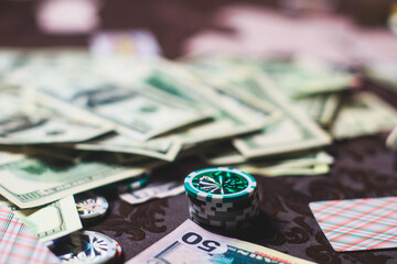 View of poker table with pack of cards, tokens, alcohol drinks, dollar money and group of gambling...