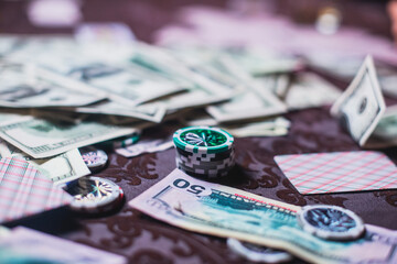 View of poker table with pack of cards, tokens, alcohol drinks, dollar money and group of gambling rich wealthy people playing poker