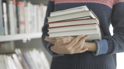 Young African American woman holding many books in hands
