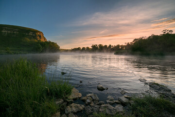 Dawn on the river. Rocky shore. Foggy morning. Sunny summer evening.