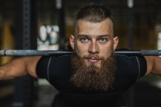 Strong and healthy man workin out with bar and weights inside a crossfit gym.