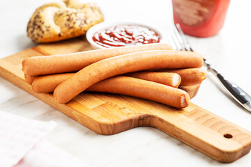 Fresh frankfurter sausages with bun and ketchup.