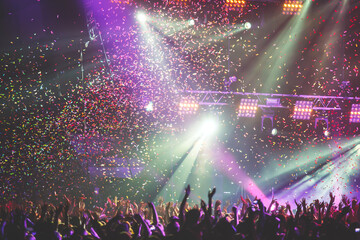 A crowded concert hall with scene stage lights, rock show performance, with people silhouettes during live music show performance with crowd of audience