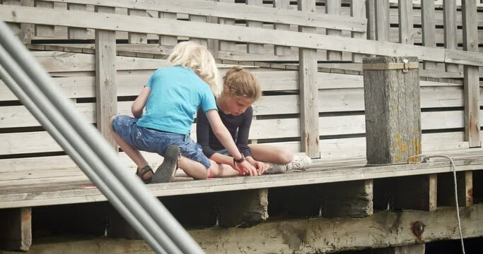 Brother And Sister Tying Bait To Fishing Line