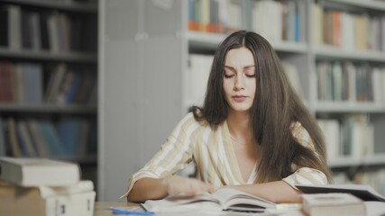 Tired brunette woman is preparing for examination at university library