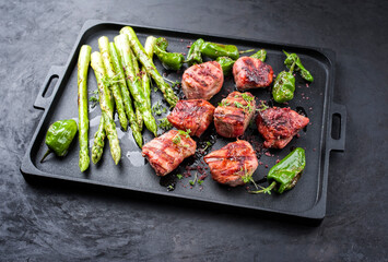 Traditional barbecue Iberian pork filet medaillons with green asparagus and chili offered as...