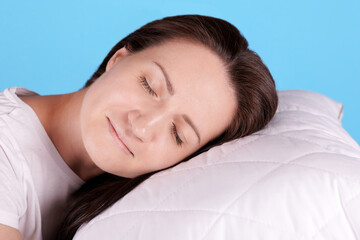 Brunette girl sleep on white pillow, closed eyes. Isolated on blue background.