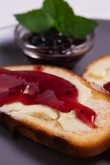 Toast with butter and blackcurrant jam decorated with mint leaves.