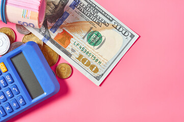 Banknote of one hundred dollars and ukrainian money near calculator on pink background
