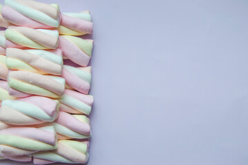 Close up picture of marshmallow in pastel shades on left side on light lavender background. Copy space concept with unhealthy sweets with amount of calories and sugar. Flat lay composition.