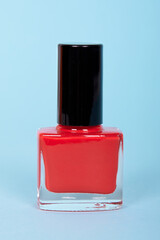 Red nail polish bottle, make up. Isolated on blue background.