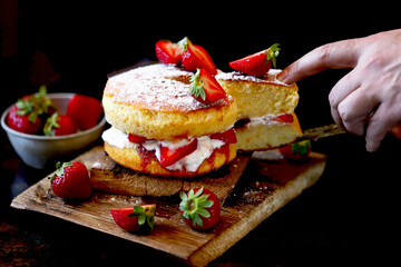 Selective focus. Strawberry Cake Sponge cake with fresh strawberries and cream. Victoria sponge cake on a dark background.