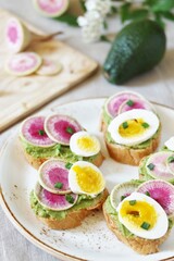 Obraz na płótnie Canvas watermelon radish sandwich with avocado and egg. healthy balanced breakfast. bright toast