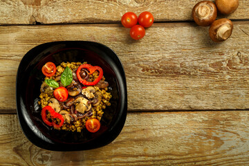 On a wooden table is a plate of boiled mung bean with vegetables and mushrooms next to vegetables. Copy space.