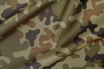 Creased camouflage fabric with pattern in green and brown colour