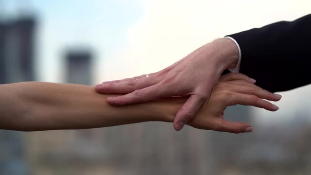 A couple in love: a man and a girl, they are on the roof against the background of the city. They take each other by the hand and let go, saying goodbye.