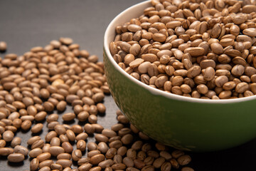 Carioquinha type beans over black background. Brazilian beans. Top view