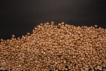 Carioquinha type beans over black background. Brazilian beans. Top view