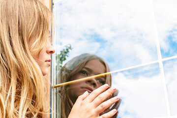The girl looks at the reflection of the window