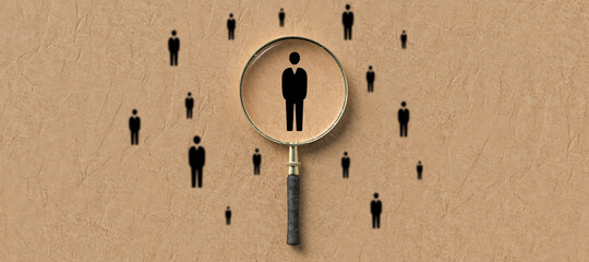 magnifying glass highlighting a person icon in a group of peoples on paper background