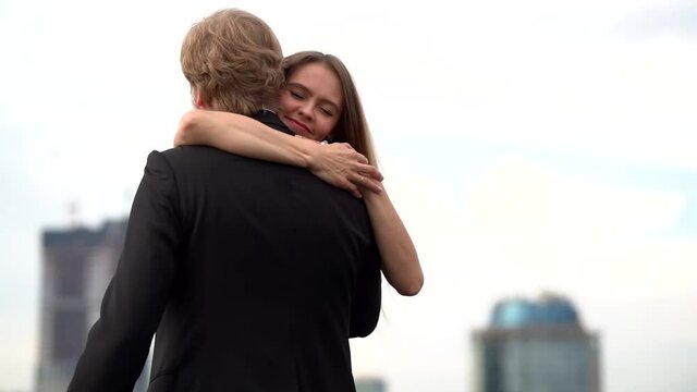 A couple in love: a bearded man in a jacket and shirt and a young slender long-haired girl in a black dress, they dance against the background of the business center and towers of Moscow city.
