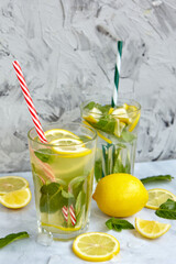Refreshing drinks for summer, cold sweet and sour lemonade juice in the glasses with sliced fresh lemons. Refreshing summer drink. Traditional lemonade with lemon, mint and ice. Selective focus