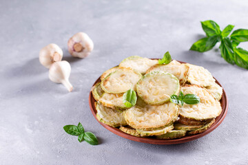 Zucchini, fried in batter with basil and garlic in a plate on a light background