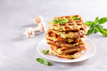 Zucchini waffle, zucchini fritters cooking on waffle maker, vegetarian zucchini waffles with basil on a plate. Copy space